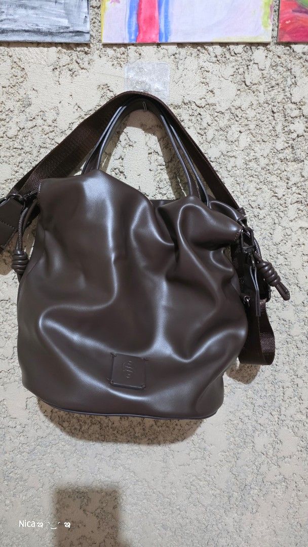 Brown Drawstring Handbag (Category: Tote Bags) located in Quezon City. Submitted by prelovedbox2016 (Listing ID 1438344403, Image 1). Description: - Brown drawstring handbag - Includes a shoulder strap - Square logo patch detail - Lined interior - Drawstring closure - Adjustable shoulder strap.