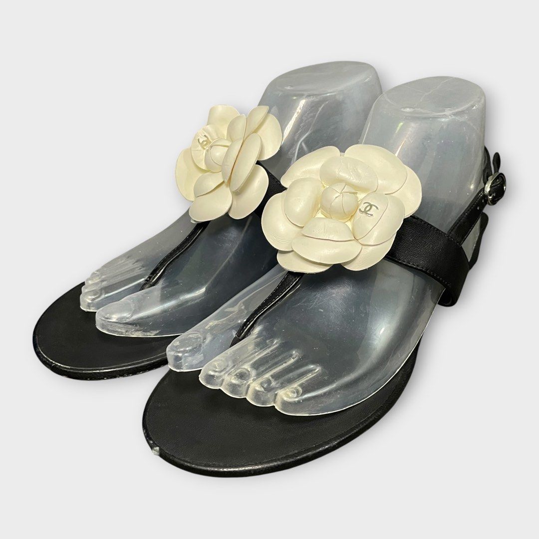 Chanel - Camellia CC Flat Leather Sandals (Category: Flats & Sandals) located in Los Banos. Submitted by declutterking (Listing ID 1438489336, Image 1). Description: Size 38C This summer, give an edge to your outfit by stepping out in these thong sandals from the house of Chanel. Crafted from black leather, this pair features a t-strap and buckle fastening at the ankle. The pair is complete with a CC-adorned Camellia flower on the front. Pair onl