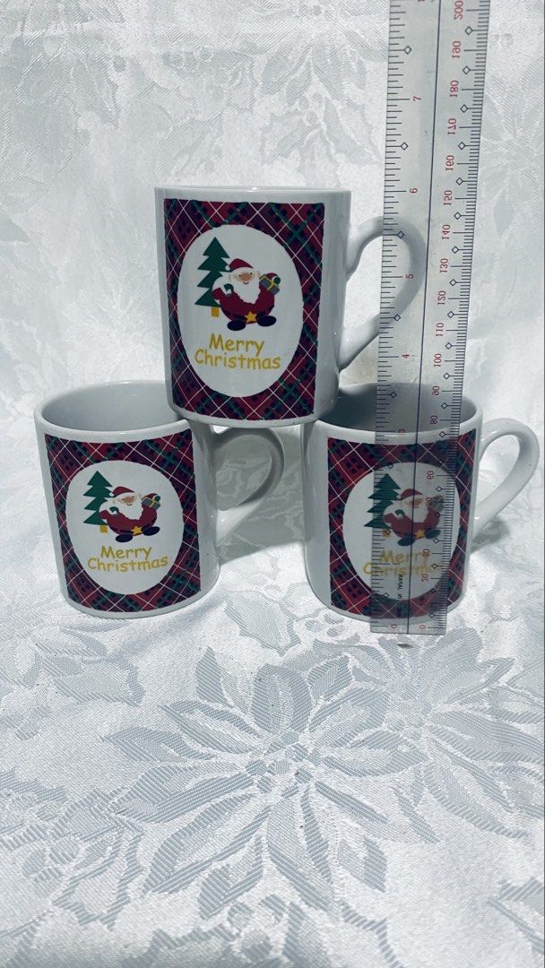 Christmas Santa Mugs (Category: Coffee & Tea Tableware) located in Quezon City. Submitted by smithram (Listing ID 1438319343, Image 1). Description: - Set of 3 white ceramic mugs - Christmas theme with Santa Claus design - Features "Merry Christmas" message - Red plaid background - Perfect for holiday beverages.