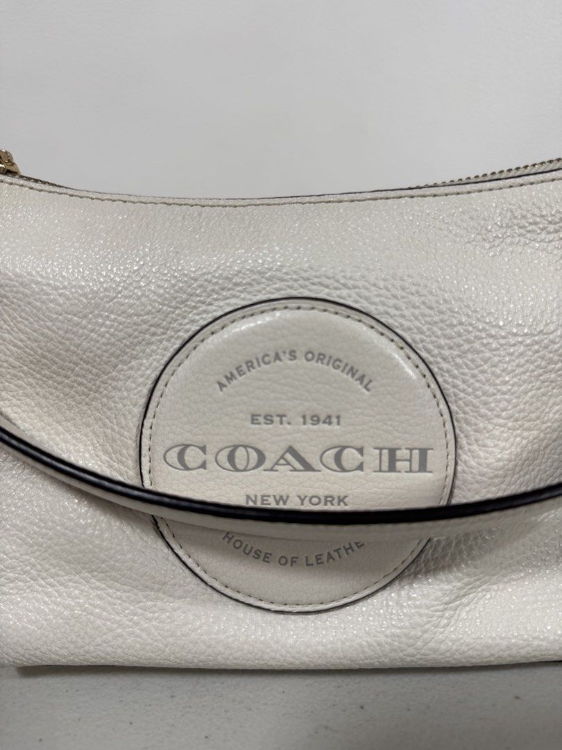 Coach Dempsey Shoulder Bag w/ Detachable Strap (Category: Luxury Bags & Wallets) located in San Fernando. Submitted by lorenz0816 (Listing ID 1438379715, Image 2). Description: - Authentic Coach shoulder bag - White textured leather exterior - Stylish circular logo detail - Detachable strap with red and black stripes - Secure zippered closure - Elegant brown interior - Includes Coach label Seldom Used Excellent Condition Guaranteed Authentic Boug