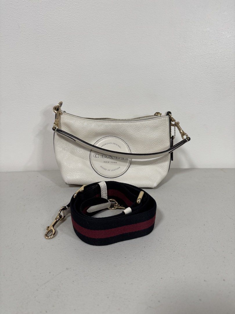 Coach Dempsey Shoulder Bag w/ Detachable Strap (Category: Luxury Bags & Wallets) located in San Fernando. Submitted by lorenz0816 (Listing ID 1438379715, Image 3). Description: - Authentic Coach shoulder bag - White textured leather exterior - Stylish circular logo detail - Detachable strap with red and black stripes - Secure zippered closure - Elegant brown interior - Includes Coach label Seldom Used Excellent Condition Guaranteed Authentic Boug