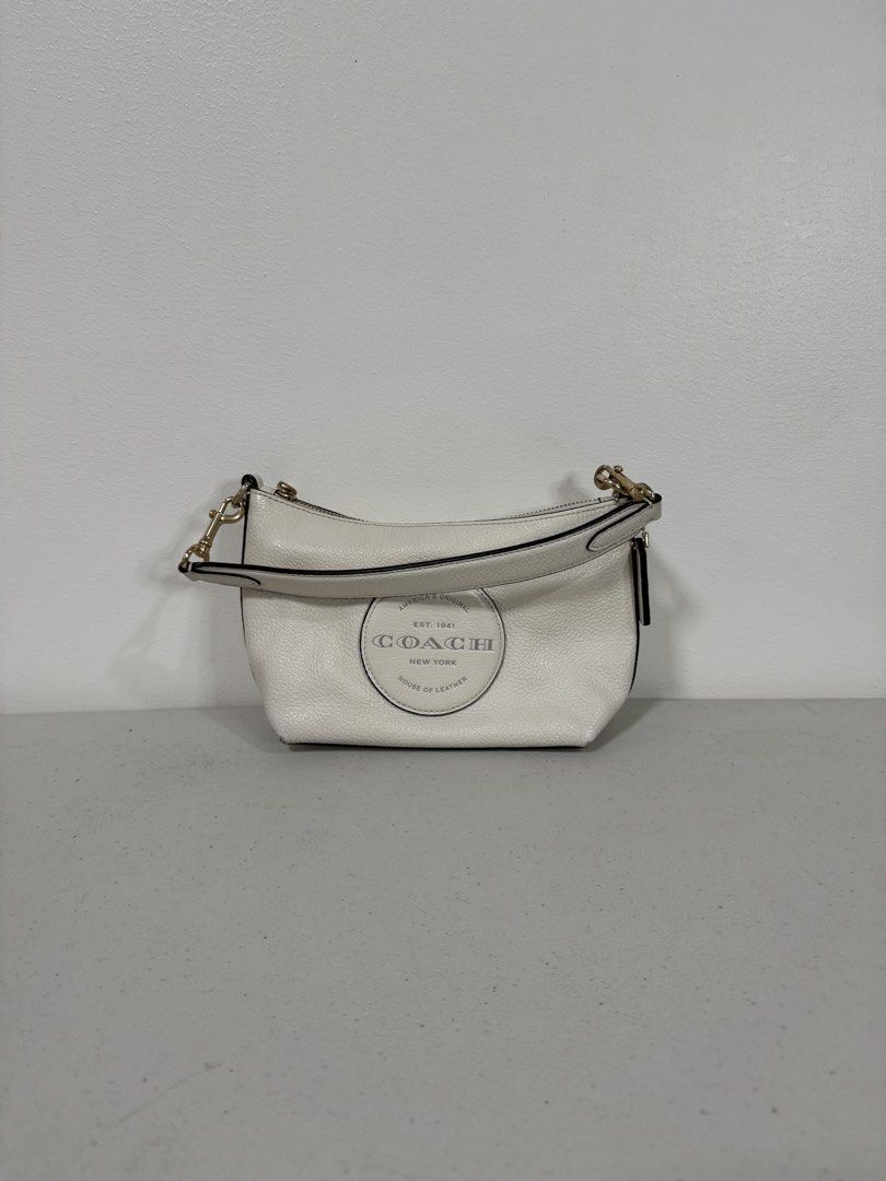 Coach Dempsey Shoulder Bag w/ Detachable Strap (Category: Luxury Bags & Wallets) located in San Fernando. Submitted by lorenz0816 (Listing ID 1438379715, Image 1). Description: - Authentic Coach shoulder bag - White textured leather exterior - Stylish circular logo detail - Detachable strap with red and black stripes - Secure zippered closure - Elegant brown interior - Includes Coach label Seldom Used Excellent Condition Guaranteed Authentic Boug