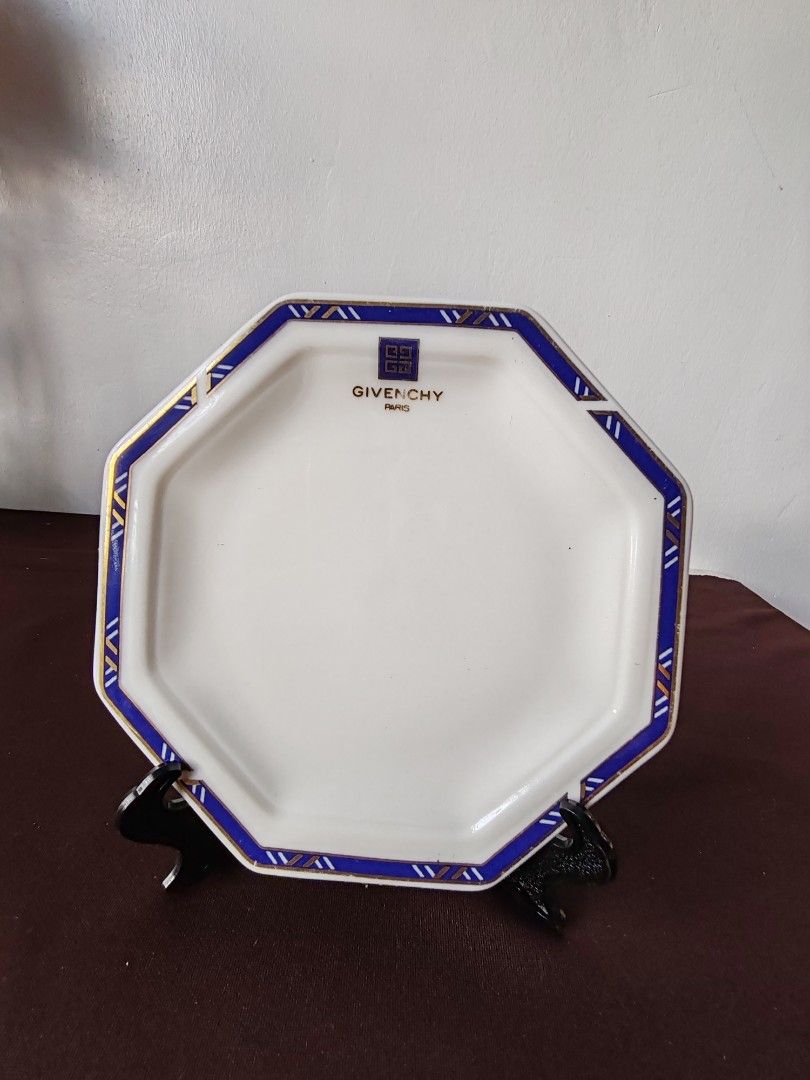 Givenchy Octagonal Plate (Category: Dinnerware & Cutlery) located in Santa Elena. Submitted by reggie022480 (Listing ID 1438396947, Image 1). Description: - Givenchy octagonal plate - Elegant design - White surface - Blue and gold border - Givenchy logo in the center - Stylish addition to any table setting or collection.