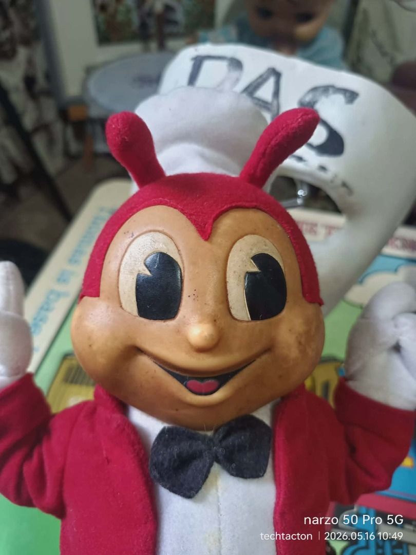 Jollibee Plush Toy (Category: Plushies & Soft Toys) located in Santo Tomas. Submitted by pickers_corner (Listing ID 1438381606, Image 2). Description: vintage 90s Jollibee Doll Rare Vinyl Plushie h26cm standing position needs cleaning as is Jollibee plush toy features the iconic mascot in its classic outfit. It has a red jacket, yellow legs, and a white chef's hat. The tag indicates it was made in China exclusively for Jollibee Foods Corporation.