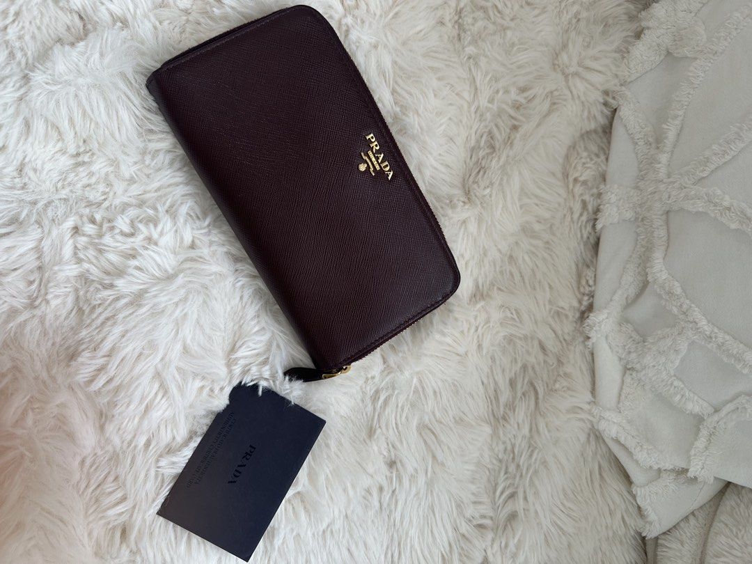 Prada Saffiano Leather Zip Around Wallet (Category: Luxury Bags & Wallets) located in Quezon City. Submitted by reginapakaiguecristobal (Listing ID 1438350471, Image 1). Description: - Authentic Prada wallet - Rich burgundy color - Made of Saffiano leather - Zip-around closure - Snap closure - Prada logo on front - Includes Prada card.