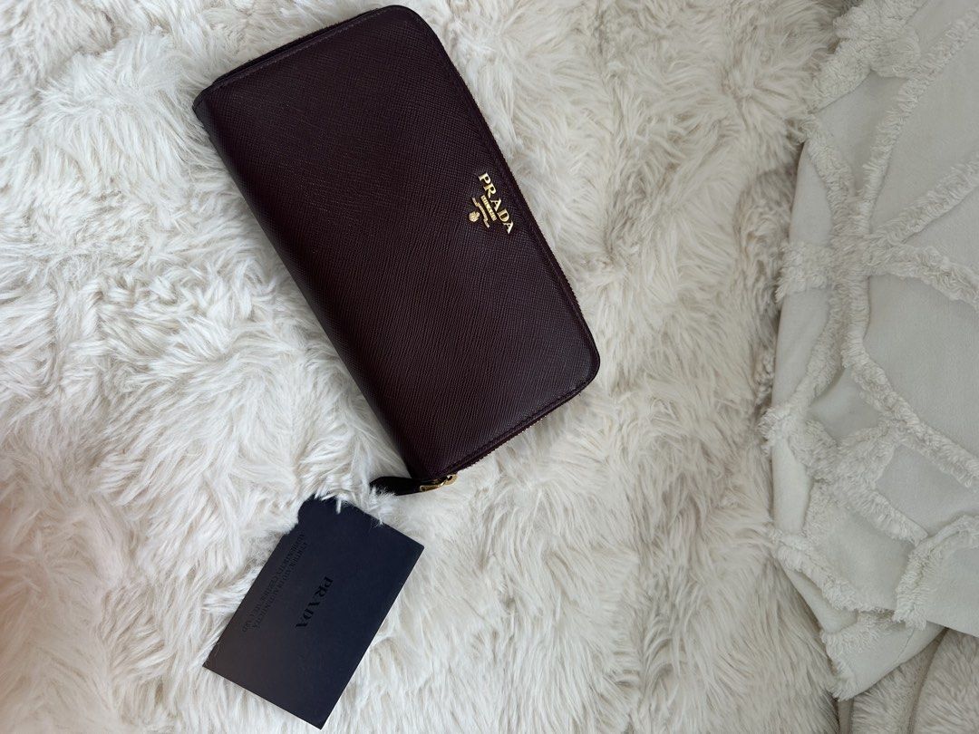 Prada Saffiano Leather Zip Around Wallet (Category: Luxury Bags & Wallets) located in Quezon City. Submitted by reginapakaiguecristobal (Listing ID 1438350471, Image 3). Description: - Authentic Prada wallet - Rich burgundy color - Made of Saffiano leather - Zip-around closure - Snap closure - Prada logo on front - Includes Prada card.