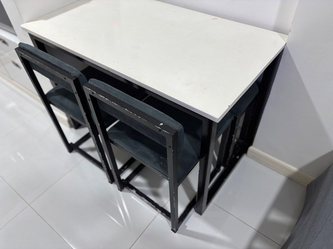 Small Dining Table for 4-5 (Category: Tables & Sets) located in Makati City. Submitted by katrina_00 (Listing ID 1438410537, Image 1). Description: - Compact dining table set - Whites tabletop with black metal frame - Includes two chairs + 1 bench - Chairs have dark grey-green cushioned seats - Table and chairs nest for space-saving storage - Great for small apartments and studios Depth: 61cm Length: 111.5cm Height: 75cm Needs a primer and paint 