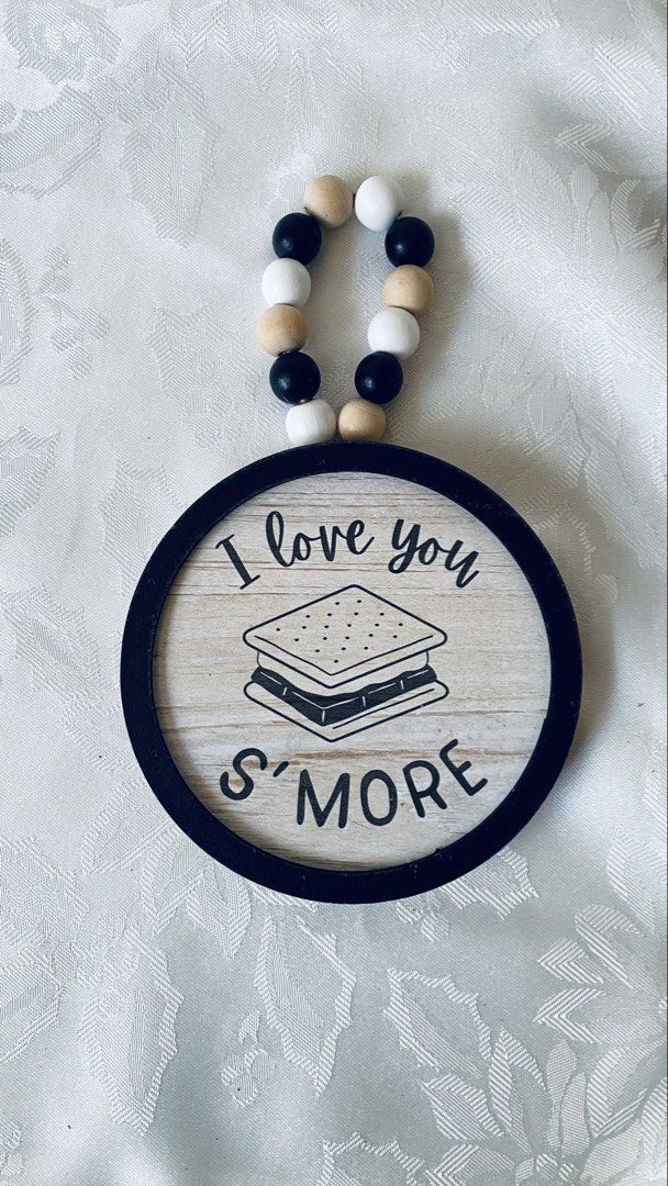 S'mores Wall Decor with Beads (Category: Wall Decor) located in Quezon City. Submitted by smithram (Listing ID 1438323941, Image 1). Description: Wall decor features a round wooden design with the words "I love you S'more" and a s'mores graphic. It has a black frame and a string of beads for hanging. The back of the decor has a wooden finish and a "Made in China" sticker..