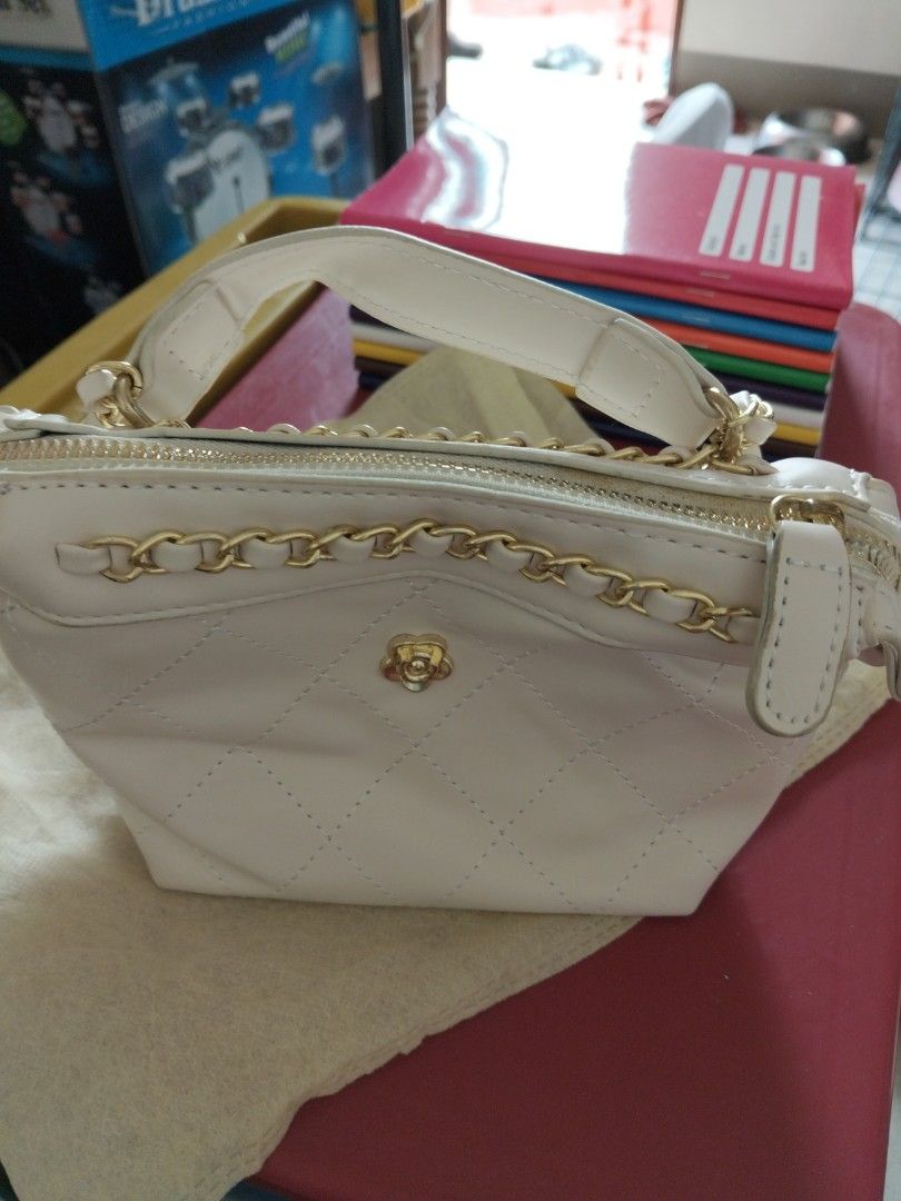 White Quilted Handbag with Gold Chain (Category: Cross-body Bags) located in Marikina City. Submitted by mbf0911 (Listing ID 1438379829, Image 2). Description: - White handbag/crossbody bag - Gold chain strap and top handle - Decorative flower emblem - Smooth, leather-like material - Zipper closure - Gold chain detail.
