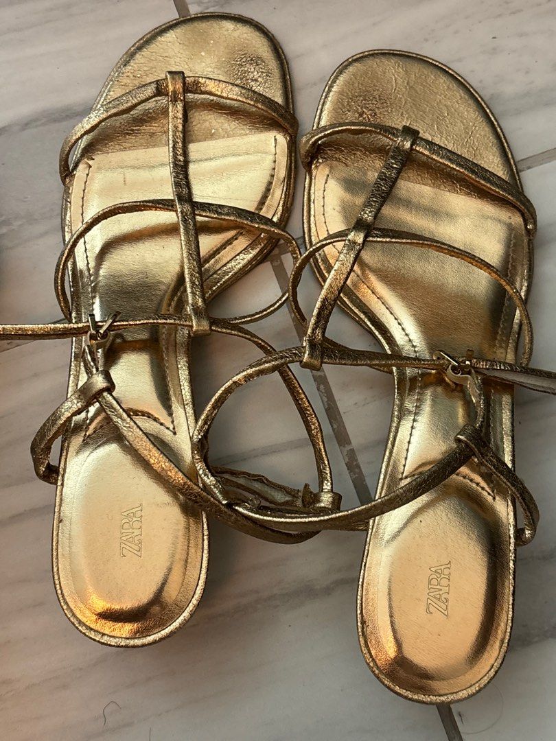 Zara Gold Strappy Sandals US 7 (Category: Flats & Sandals) located in Quezon City. Submitted by secondhandcommunity (Listing ID 1438320645, Image 1). Description: - Zara gold strappy sandals - Low block heel - Multiple straps for secure fit - Metallic finish - Zara logo on footbed - Adds elegance to any outfit - No box.