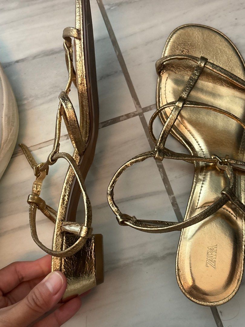 Zara Gold Strappy Sandals US 7 (Category: Flats & Sandals) located in Quezon City. Submitted by secondhandcommunity (Listing ID 1438320645, Image 2). Description: - Zara gold strappy sandals - Low block heel - Multiple straps for secure fit - Metallic finish - Zara logo on footbed - Adds elegance to any outfit - No box.