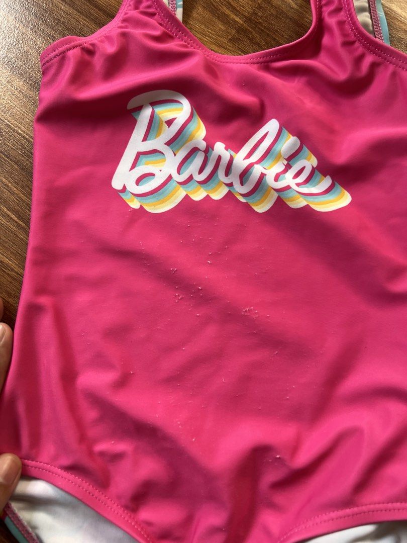 Barbie Swimsuit Set (Category: Bikinis & Swimsuits) located in Caloocan City. Submitted by pmaerc (Listing ID 1438594205, Image 3). Description: - Two Barbie swimsuits for kids. - One is pink with the Barbie logo; shows some wear on the front. - The other is black with pink accents and a zipper. - Both swimsuits have a Barbie logo. -Pink size small: Black size medium.