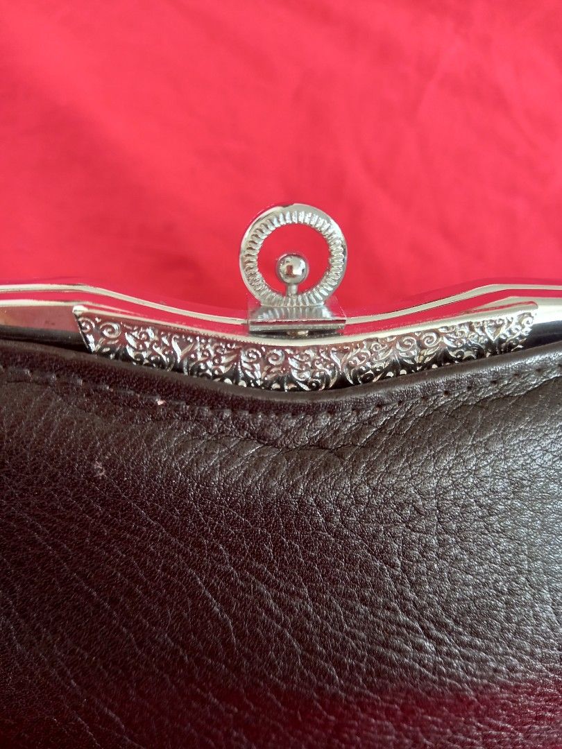 Brown Leather Clutch with Silver Accents (Category: Clutches) located in Tuguegarao City. Submitted by zenphoenix-7ad615 (Listing ID 1438565694, Image 3). Description: - Brown leather clutch - Silver clasp with intricate detailing - Rectangular shape with curved top - Genuine leather material - Ring closure on clasp - A stylish accessory 22 cm by 11 cm.