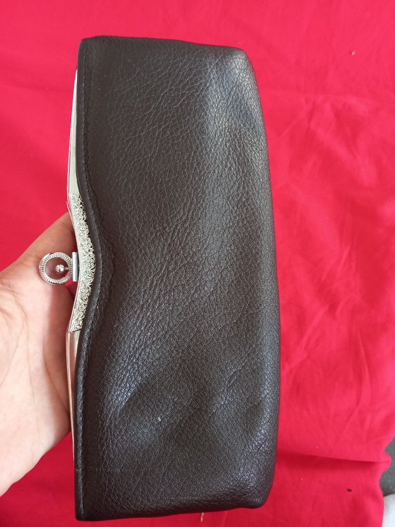 Brown Leather Clutch with Silver Accents (Category: Clutches) located in Tuguegarao City. Submitted by zenphoenix-7ad615 (Listing ID 1438565694, Image 1). Description: - Brown leather clutch - Silver clasp with intricate detailing - Rectangular shape with curved top - Genuine leather material - Ring closure on clasp - A stylish accessory 22 cm by 11 cm.