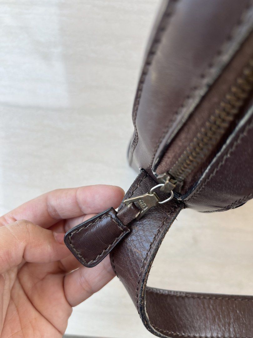 Celine Brown Leather Crossbody Bag (Category: Luxury Bags & Wallets) located in Bulacan. Submitted by dearsybella (Listing ID 1438554073, Image 3). Description: Brown leather crossbody bag with a curved design. Features a top zipper closure and an adjustable strap with a gold-tone buckle. The bag has a stitched detail along the top and a small pocket inside. The interior is lined with brown fabric. The Celine logo is visible on the buckle..