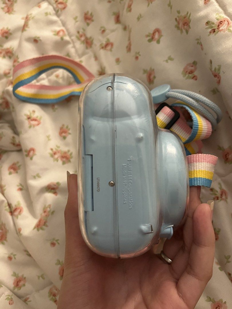 Fujifilm Instax Mini 11 - Sky Blue (Category: Cameras) located in Tagum. Submitted by butterfinger21 (Listing ID 1438687445, Image 3). Description: - Fujifilm Instax Mini 11 in Sky Blue - Includes matching strap with colorful design - Comes with a clear protective case - Focus range: 0.3m to infinity - Instax logo visible.