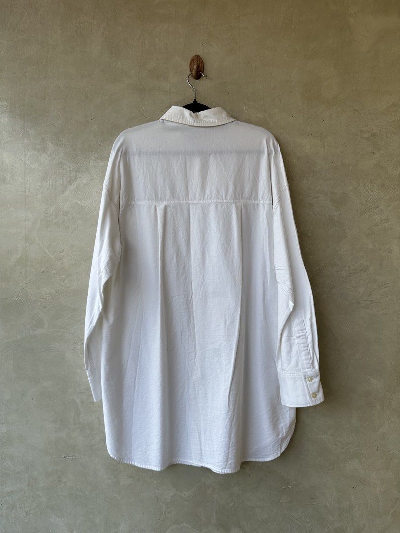 GU White Oversized Shirt - Size M (Category: Shirts) located in Cavite. Submitted by hand.picked (Listing ID 1438627699, Image 3). Description: - GU white oversized shirt - Features: Classic collar, button-down, chest pocket - Sleeves: Long with buttoned cuffs - Fit: Relaxed, longer length - Fabric: Lightweight - Ideal for casual wear - Oxford Size: Medium Dimension: 23” Width / 34” Length Condition: Excellent.