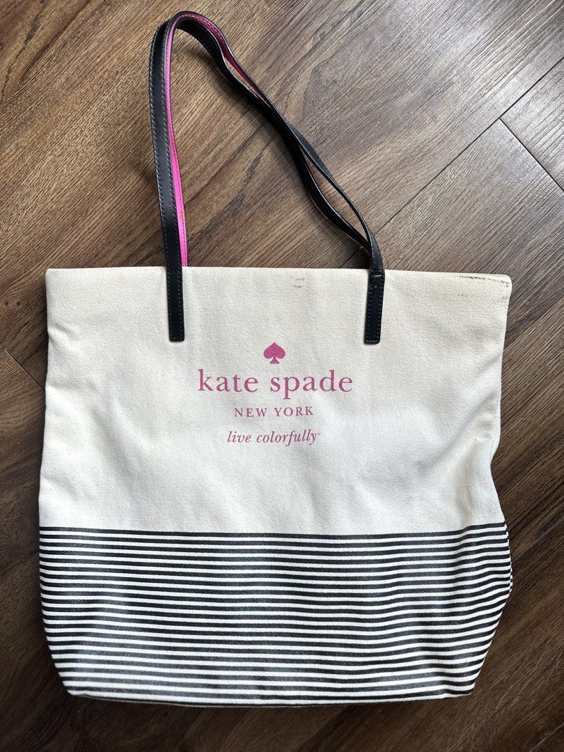 Kate Spade New York Tote Bag (Category: Tote Bags) located in Mandaluyong City. Submitted by TheWeekendProject (Listing ID 1438566438, Image 1). Description: - Kate Spade tote bag - Black and white striped bottom - Black handles with pink accents - Cream-colored body - Pink Kate Spade logo - Visible stains on exterior - Suitable for everyday use.