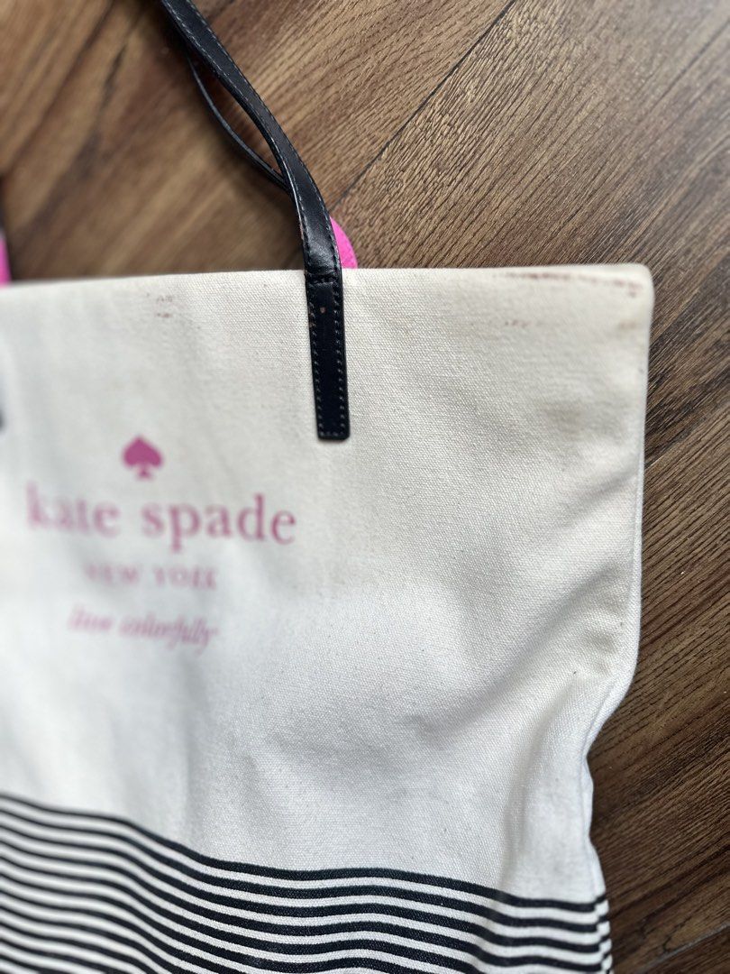 Kate Spade New York Tote Bag (Category: Tote Bags) located in Mandaluyong City. Submitted by TheWeekendProject (Listing ID 1438566438, Image 2). Description: - Kate Spade tote bag - Black and white striped bottom - Black handles with pink accents - Cream-colored body - Pink Kate Spade logo - Visible stains on exterior - Suitable for everyday use.