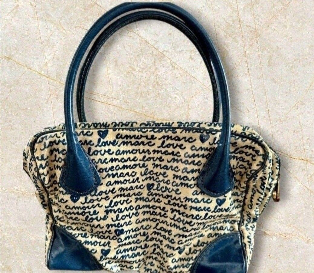 Marc by Marc Jacobs Love Amour Handbag (Category: Purses & Pouches) located in Quezon City. Submitted by kcobs (Listing ID 1438649327, Image 3). Description: - Cream-colored fabric - Authentic Marc Jacobs doctors bag - Navy blue "love amour marc" print - Navy blue handles and trim - Brand name metal plate - Rectangular shape - Zipper closure.