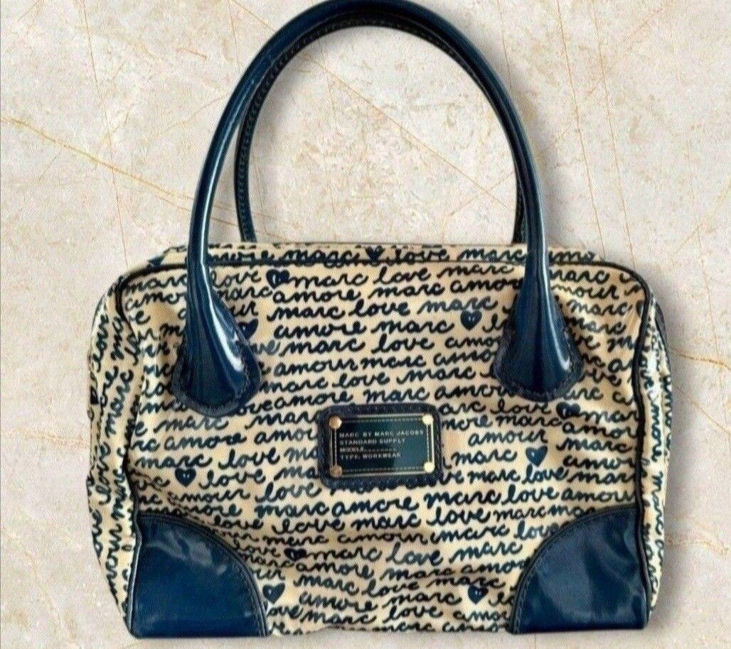 Marc by Marc Jacobs Love Amour Handbag (Category: Purses & Pouches) located in Quezon City. Submitted by kcobs (Listing ID 1438649327, Image 1). Description: - Cream-colored fabric - Authentic Marc Jacobs doctors bag - Navy blue "love amour marc" print - Navy blue handles and trim - Brand name metal plate - Rectangular shape - Zipper closure.