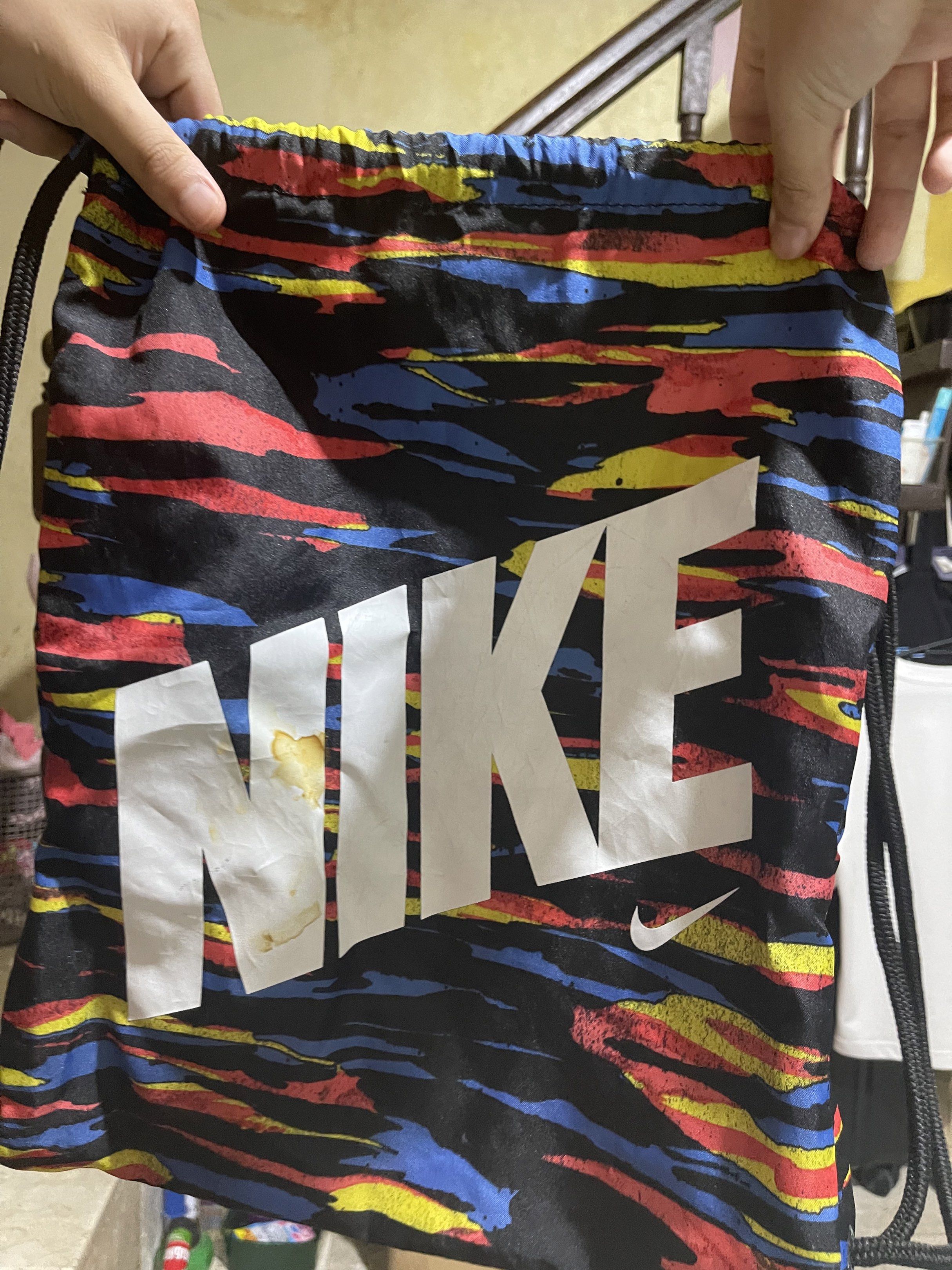 Nike Drawstring Bag (Category: Backpacks) located in Quezon City. Submitted by rish40 (Listing ID 1438667560, Image 1). Description: - Nike drawstring bag - Colorful pattern - Large Nike logo - Black drawstrings - Lightweight material - Minor stains present.