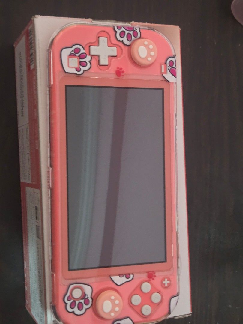 Nintendo Switch Lite Coral with Cat Case (Category: Nintendo) located in Manila. Submitted by clodmnyu (Listing ID 1438576725, Image 1). Description: - Coral Nintendo Switch Lite console - Includes a cute cat-themed case - Case features paw prints and cat design - Package includes console and case.