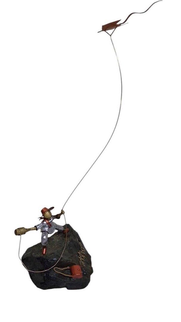 Saranggola by Jerome Sta Ana (Category: Other Home Decor) located in Taguig. Submitted by muntingkahon (Listing ID 1438648589, Image 2). Description: - Unique metal sculpture - Depicts a person climbing a rock with a kite - Intricate details - Includes a small red bag and a hat - Person is wearing a suit H 41 W22 L13” - Mounted on a dark rock base.