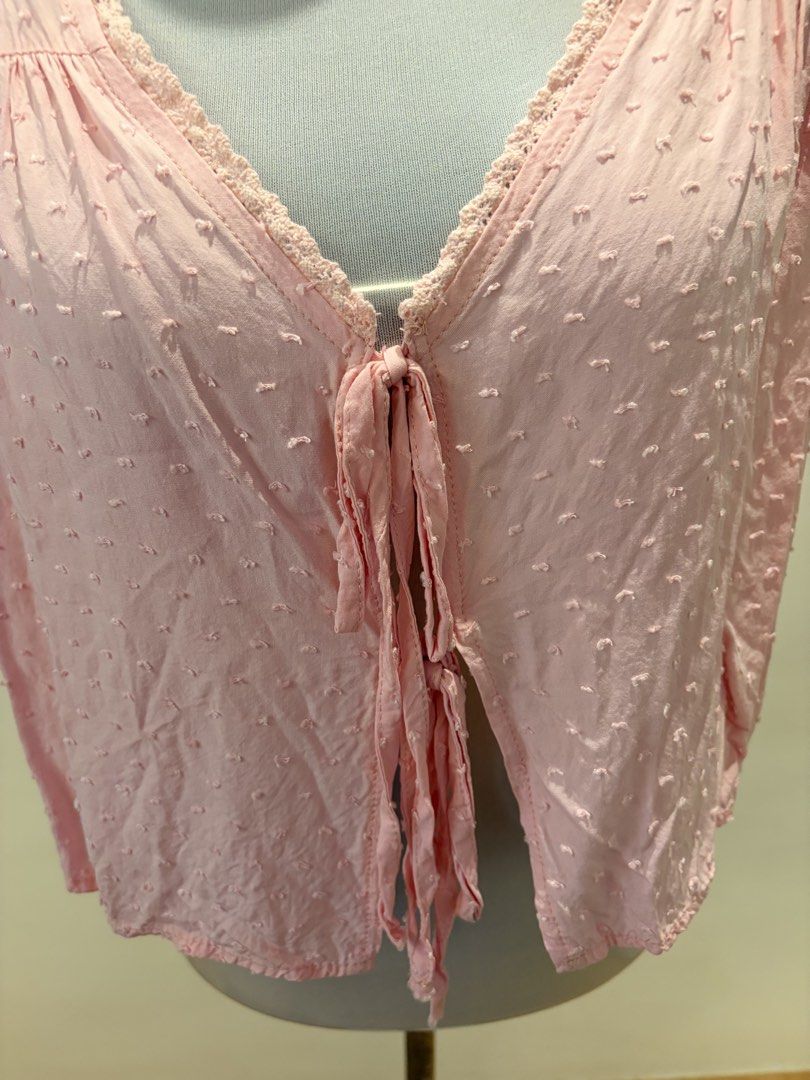 SHEIN Pink Cropped Top with Tie (Category: Blouses) located in Quezon City. Submitted by ninas_preloved (Listing ID 1438598844, Image 2). Description: Cropped top features a delicate pink color and a flattering V-neckline. It has short sleeves and a tie closure at the front. The fabric has a subtle textured pattern. The top is designed with a cropped length, making it a versatile piece for various outfits..