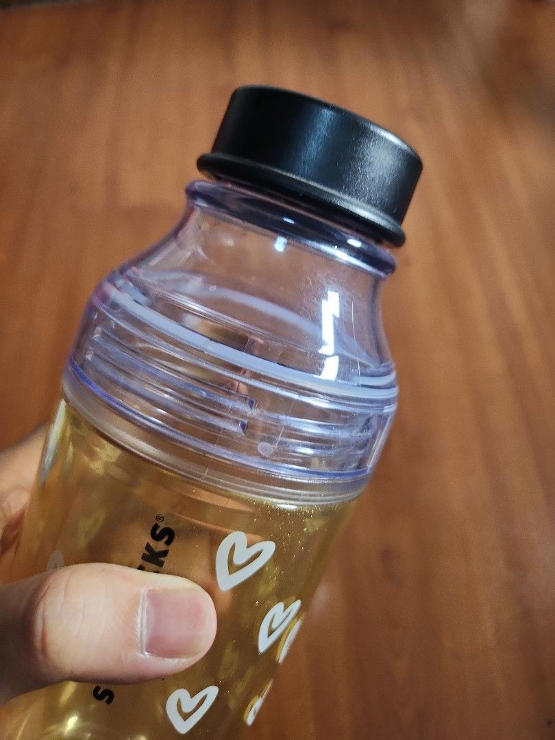 Starbucks Heart Design Water Bottle (Category: Water Bottles & Tumblers) located in Manila. Submitted by jochaaa011 (Listing ID 1438623762, Image 3). Description: - Starbucks water bottle - Heart design - Clear plastic body with gold interior - Black screw-on lid - 473ml capacity - Starbucks logo on the bottom.