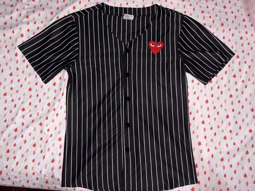 Comme des Garçons Striped short sleeve button down shirt (Category: Shirts) located in Manila. Submitted by fierce_denclutter (Listing ID 1438641783, Image 1). Description: - Black and white striped baseball shirt - Features a red heart patch - V-neck design - Button-up closure - Short sleeves - Length: Approximately 27 inches - Chest width: Approximately 35 inches.