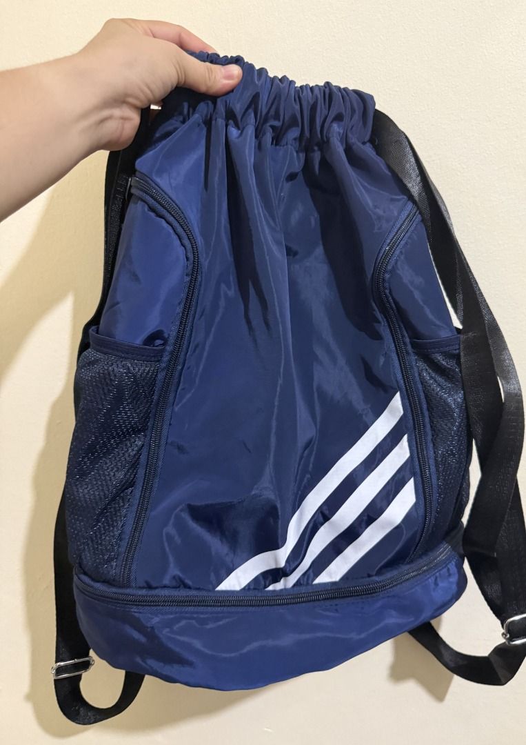 Adidas Drawstring Backpack with Side Pockets (Category: Backpacks) located in Caloocan City. Submitted by jansenhidalgo (Listing ID 1438742155, Image 1). Description: Adidas drawstring backpack in navy blue. Features white stripes, side pockets, and a bottom zippered compartment. Adjustable shoulder straps. Great for sports or everyday use..