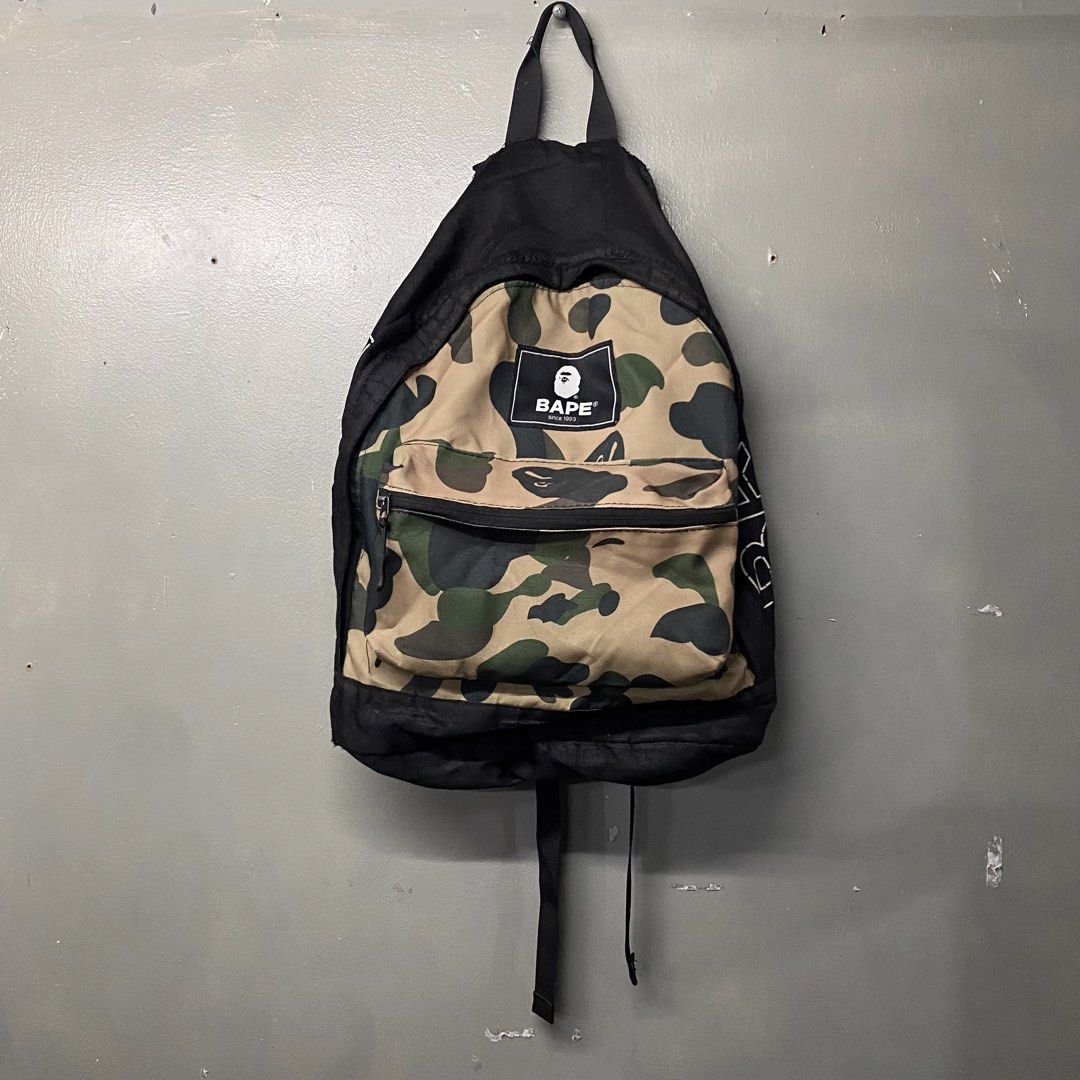 BAPE Camo Backpack (Category: Backpacks) located in Cagayan de Oro. Submitted by sumamestreethub (Listing ID 1438838851, Image 1). Description: - Authentic BAPE backpack - Distinctive camo pattern on front pocket - Black body with BAPE logo - Top handle and adjustable shoulder straps - Front pocket and spacious main compartment - Clean and well-maintained interior.