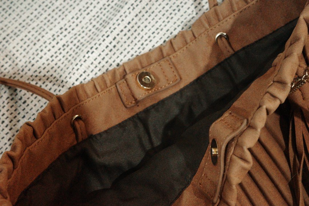 Brown Pleated Tote Bag with Tassel (Category: Tote Bags) located in Quezon City. Submitted by decluttering.neyns (Listing ID 1438713029, Image 3). Description: - Stylish brown tote bag - Pleated design - Magnetic snap closure - drak brown interior lining - Small interior zippered pocket - Long straps for shoulder or hand carry - Decorative tassel and chain detail.