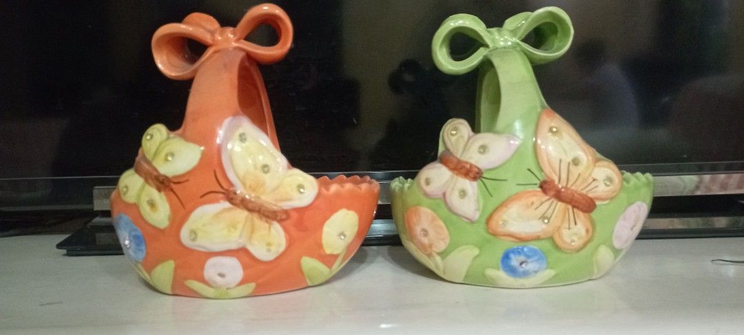 Butterfly Ceramic Wall Planters (Category: Wall Decor) located in Manila. Submitted by cool_niacene15 (Listing ID 1438797979, Image 1). Description: - Set of two ceramic wall planters - Features butterfly and floral designs - Colors: Green and orange - Design: Bow-shaped base and scalloped rim - Ideal for small plants or decorative items - Adds a whimsical touch to any space - 13 x 14 x 15 cm .