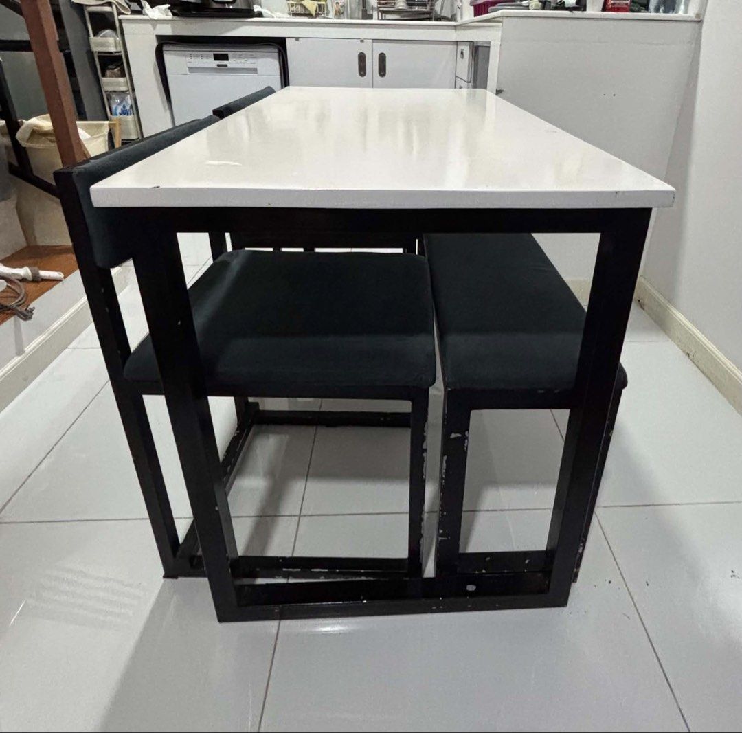 Dining Table Set with 2 Chairs and Bench (Category: Tables & Sets) located in Makati City. Submitted by Aninipot (Listing ID 1438849133, Image 2). Description: - Compact dining table set - Whites tabletop with black metal frame - Includes two chairs + 1 bench - Chairs have dark grey-green cushioned seats - Table and chairs nest for space-saving storage - Great for small apartments and studios Depth: 61cm Length: 111.5cm Height: 75cm Needs a prime