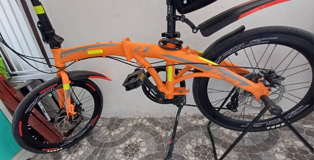 Trinx Dolphin 2.0 Foldable Bike (Category: Bicycles) located in Bacoor. Submitted by ricks01 (Listing ID 1438811637, Image 2). Description: - Trinx Dolphine 2.0 foldable bike - Black tires and disc brakes. Black seat with storage bag - Front and rear fenders. Handlebars with phone mount - Bike stand included - Some scratches and stains due to wear and tear..