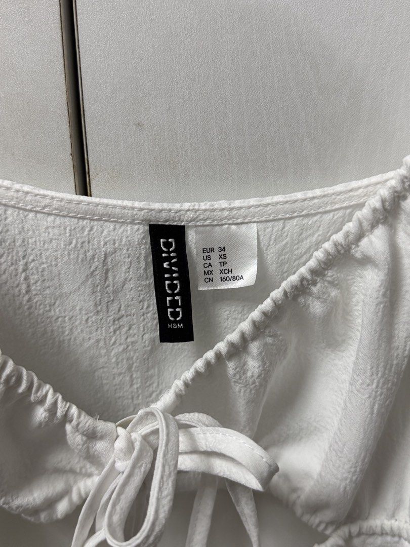 H&M Divided White Dress XS (Category: Dresses) located in Quezon City. Submitted by biuesides (Listing ID 1438713439, Image 2). Description: - H&M Divided white mini dress - Square neckline with tie detail - Puff sleeves - Mini length - Size: XS - Textured fabric.