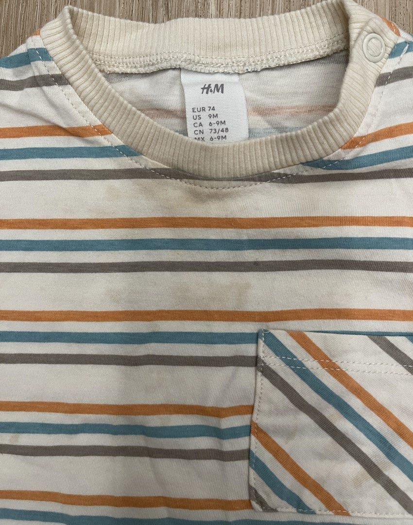 H&M Striped T-shirt - 9M (Category: Babies & Kids Fashion) located in Makati City. Submitted by riz.gspr (Listing ID 1438760922, Image 2). Description: - H&M baby t-shirt - Size: 74 (fits approximately 9 months) - Design: Striped with a pocket - Colors: Orange, blue, and gray stripes on a white background - Features: Short sleeves, round neckline.