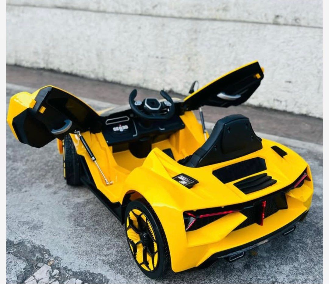 Lamborghini kids electric car with remote control (Category: Kids Toys) located in Manila. Submitted by cutielove888 (Listing ID 1438749520, Image 3). Description: - Yellow ride-on car - Features gullwing doors - Sporty design - Includes steering wheel - Detailed wheels - Designed for children - Likely battery-powered - Sleek, modern look with black accents and headlights.