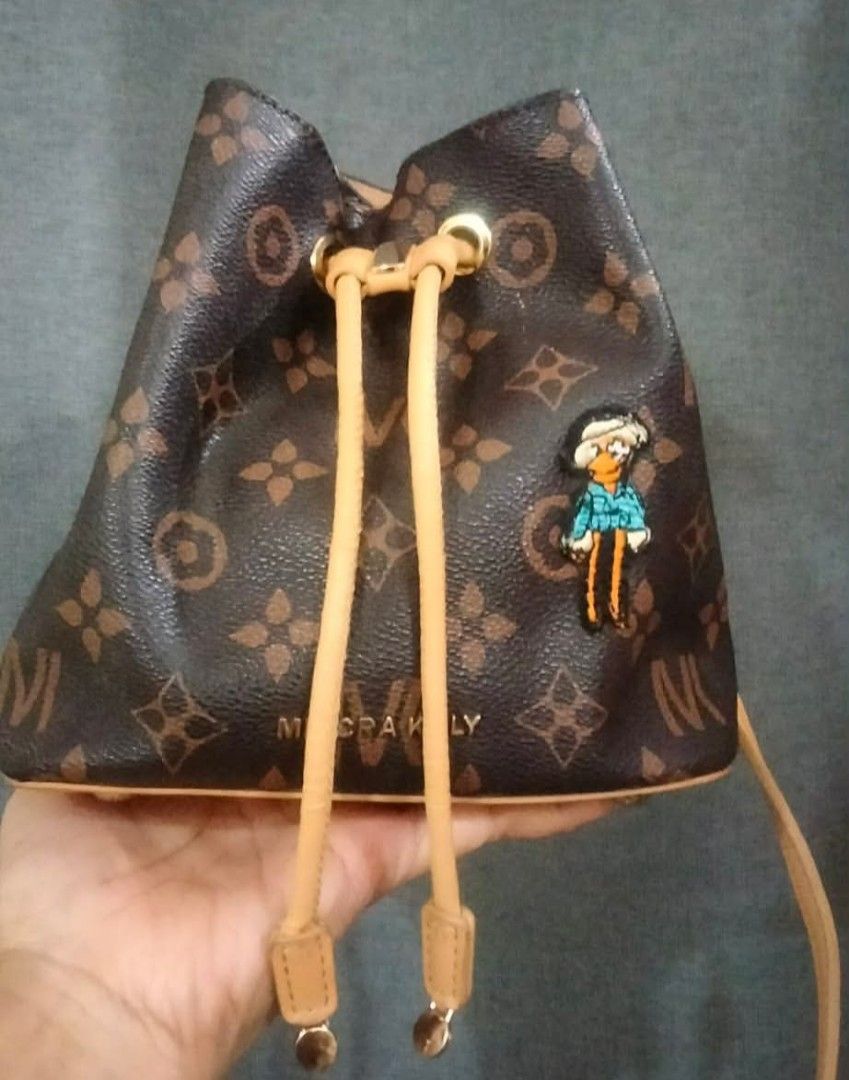 Mini Bucket Bag with Cartoon Patch (Category: Luxury Bags & Wallets) located in Cabanatuan. Submitted by almaespino24263 (Listing ID 1438861778, Image 2). Description: - Mini bucket bag - Brown monogram pattern - Drawstring closure - Tan strap - Cartoon patch - Leather-like material - Stylish and compact - Ideal for everyday use.