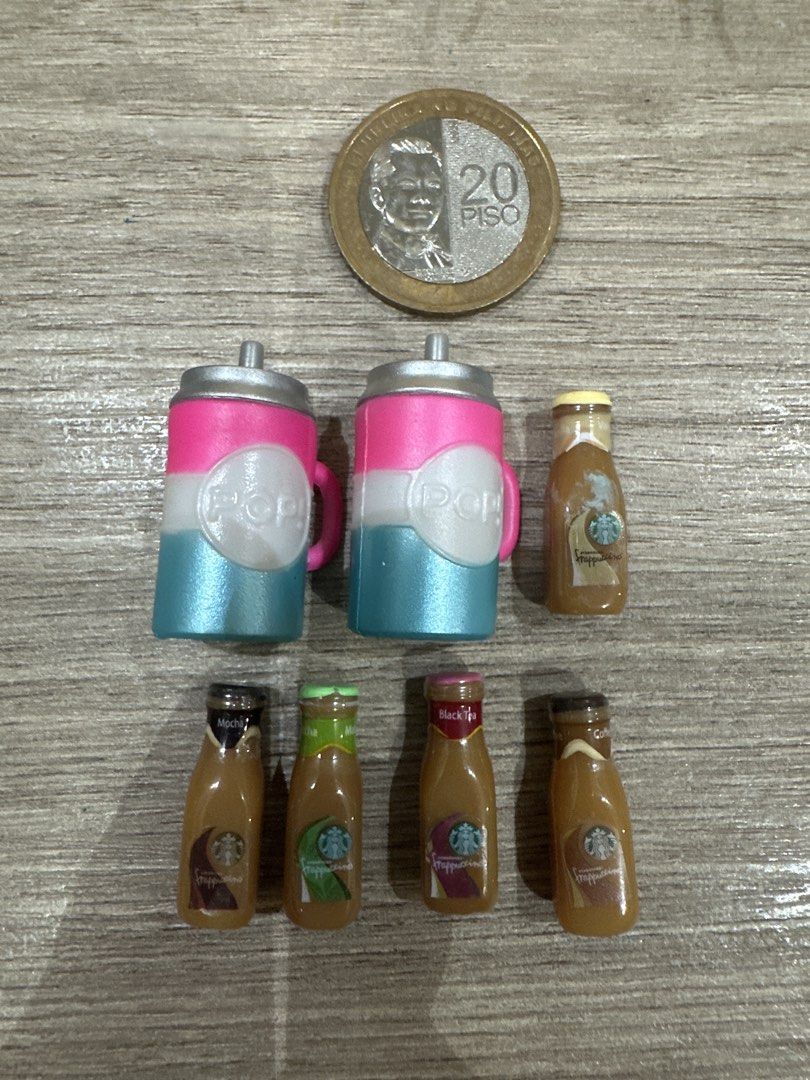 Miniature Starbucks and Pop Bottles (Category: Water Bottles & Tumblers) located in Muntinlupa City. Submitted by camotepie (Listing ID 1438829623, Image 1). Description: - Miniature bottle collection - Includes: - Two Pop bottles (with handles and lids) - Five Starbucks bottle designs (various label colors and designs) - Size reference: 20 Piso coin.