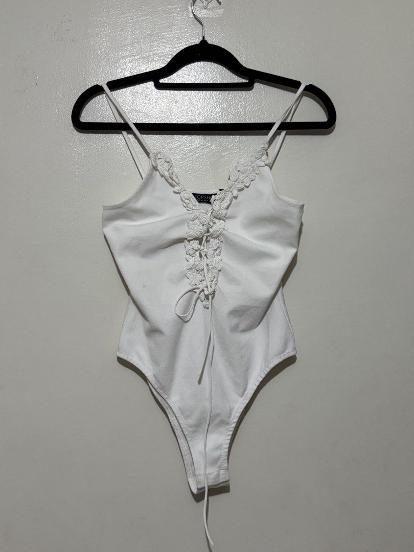 Topshop White Lace-Up Bodysuit (Category: Others Tops) located in Quezon City. Submitted by maxmaximoo (Listing ID 1438878782, Image 1). Description: - Topshop white bodysuit - Lace-up detail - Delicate lace trim - Scoop neckline and spaghetti straps - Size: EUR 36, UK 8, US 4 - Made in Romania - Smooth, solid white fabric.