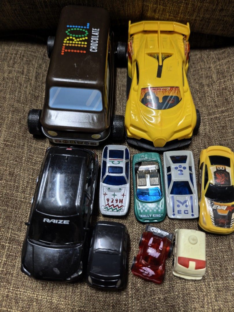 Assorted Toy Cars (Category: Vehicle & Diecast Models) located in Rizal. Submitted by gkstcenit (Listing ID 1435604627, Image 2). Description: - Assorted toy car collection - Includes: brown truck with "CHOCOLATE" text, yellow sports car, black "RAIZE" car, and smaller cars in a tin container - Features racing-themed graphics - Perfect for collectors or kids.