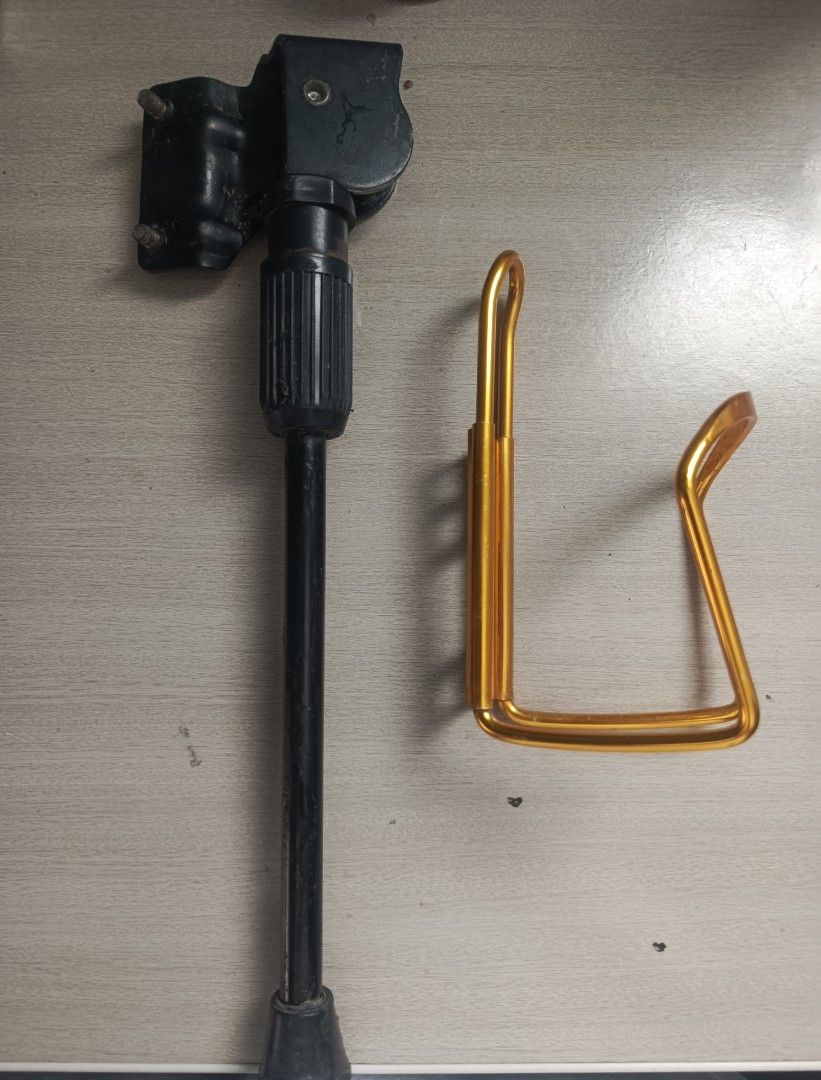 Bike Kickstand and Bottle Cage (Category: Bicycles) located in Manila. Submitted by bei.ru (Listing ID 1435676468, Image 2). Description: - Black, adjustable metal bike kickstand included. - Gold bottle cage for standard water bottles. - Both items enhance bike functionality. - Compatible with most bicycles..