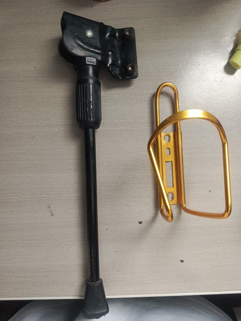 Bike Kickstand and Bottle Cage (Category: Bicycles) located in Manila. Submitted by bei.ru (Listing ID 1435676468, Image 1). Description: - Black, adjustable metal bike kickstand included. - Gold bottle cage for standard water bottles. - Both items enhance bike functionality. - Compatible with most bicycles..