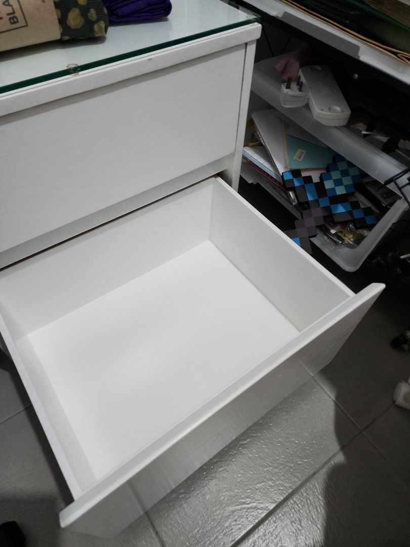 Solid Wood White Bedside Cabinet with Glass Top 40x50cm (Category: Shelves, Cabinets & Racks) located in Makati City. Submitted by tongpatsu (Listing ID 1435622366, Image 3). Description: - White cabinet - Two drawers - Tempered glass top - Castor wheels - White - Suitable for bedroom or office - Rectangular shape (40x50x56cm) - Clean aesthetic.