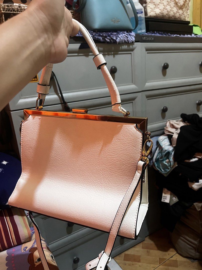 Dune London Handbag (Category: Luxury Bags & Wallets) located in Paranaque City. Submitted by maineshar19 (Listing ID 1435576056, Image 2). Description: - Dune London handbag - Light pink, textured exterior - Structured design - Top handle and detachable shoulder strap - Gold-tone frame and clasp - Black fabric lining - Interior zippered pocket.