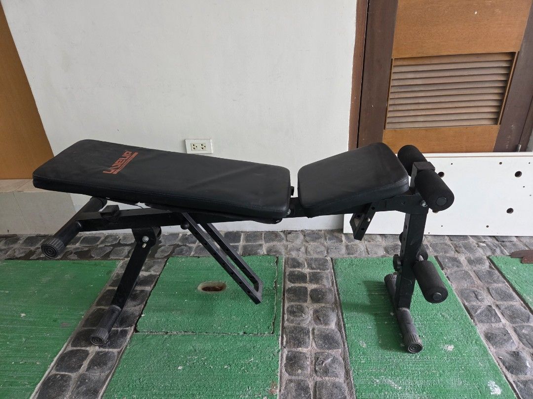 Liveup Adjustable Weight Bench (Category: Weights & Dumbbells) located in Taguig. Submitted by shoptiludrop888 (Listing ID 1435598402, Image 1). Description: - Liveup adjustable weight bench - Adjustable backrest and leg support - Black with red Liveup branding - Foldable design for easy storage - Includes foam rollers for leg support - Suitable for various exercises.