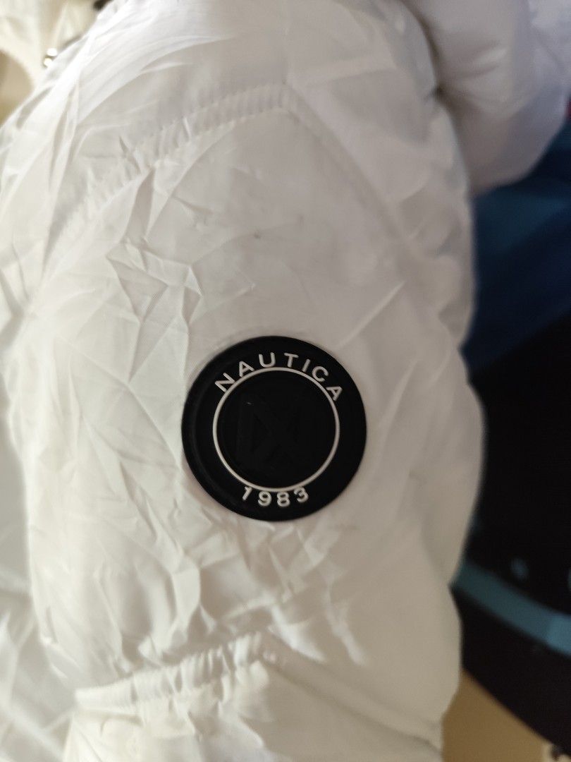 Nautica White Puffer Jacket with Hood (Category: Coats, Jackets and Outerwear) located in Compostela. Submitted by fashiondeamar (Listing ID 1435607816, Image 3). Description: - White Nautica puffer jacket - Fur-lined hood - Zip-up front - Two zippered pockets - Nautica logo on sleeve - Water-resistant - Size: XS/EUR S/MEX S - Quilted design - Black cuffs - Made in Vietnam.